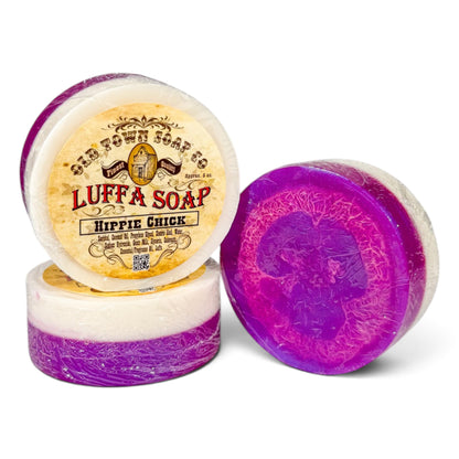 Three round bars of Luffa Soap from Old Town Soap Co. on a white background, featuring a purple and white layered design with one bar showing its vintage-style paper label.